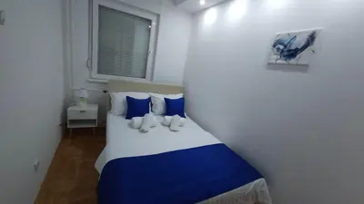 a bedroom with a bed with blue and white pillows at Nele in Bežanija