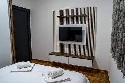 a bedroom with a tv and a bed with towels at Apartman ISKRA - Velvet in Arandjelovac