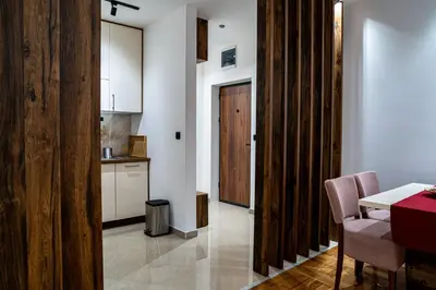 a kitchen with a table and a wooden door at Apartman ISKRA - Velvet in Arandjelovac