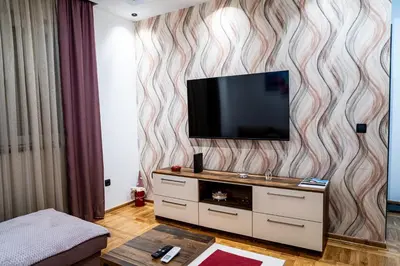 a living room with a television on a wall at Apartman ISKRA - Velvet in Arandjelovac