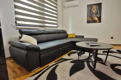 a living room with a black leather couch and a table at Malisic apartmani Vračar in Vračar (historical)