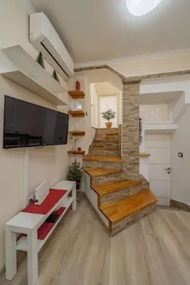 a living room with a staircase with a tv and a stair case at Megi Zemun Apartment in Zemun