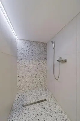a shower in a bathroom with a tile floor at Keti Zemun Spa Apartment in Zemun