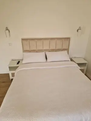 a large bed in a room with two tables at Apartman Bika in Surčin
