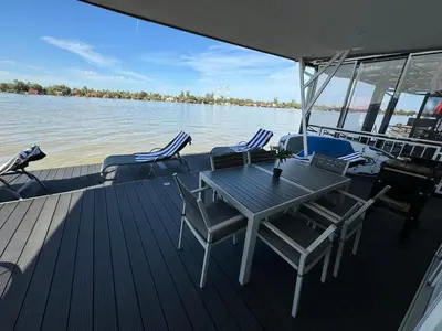 a wooden deck with a table and chairs on a boat at Beautiful houseboat on the Sava river in Belgrade