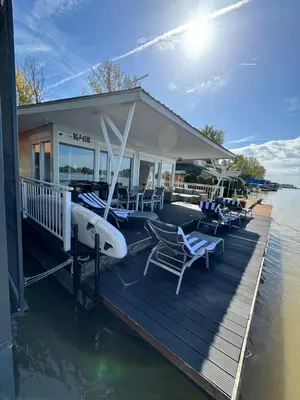 a dock with chairs and a house on the water at Beautiful houseboat on the Sava river in Belgrade