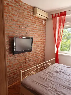 a bedroom with a brick wall with a tv on the wall at Zvezda in Karaburma