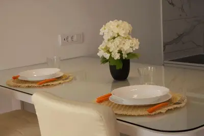 a table with two plates and a vase of white flowers at Airport Studio Stefan in Belgrade