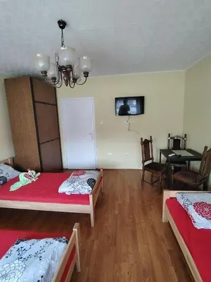 a room with two beds and a dining room with a table at STD Havela in Kovačica