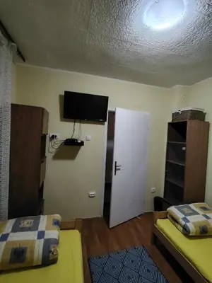 a room with two beds and a television on the wall at STD Havela in Kovačica
