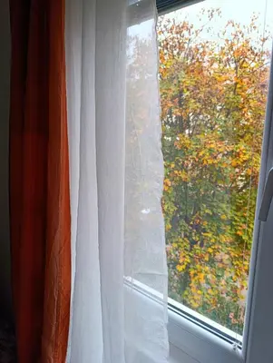 a window with a white curtain and a view at Apartman Dora in Ruma