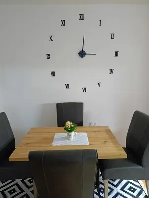 a dining room table with chairs and a clock on the wall at Apartman Dora in Ruma
