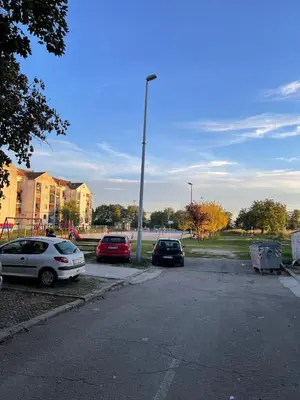 a parking lot with three cars parked next to a light pole at Apartman Dora in Ruma