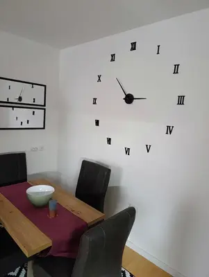 a dining room table with a clock on the wall at Apartman Dora in Ruma