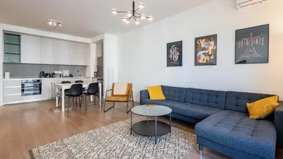 a living room with a blue couch and a kitchen at Belgrade Waterfront Quartet 1 in Belgrade