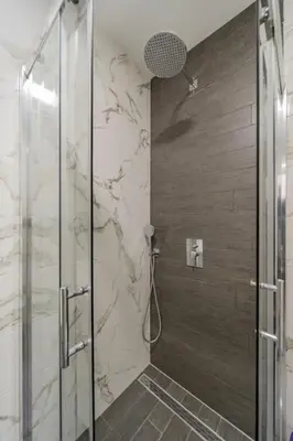 a bathroom with a shower with a glass door at Hemingway Belgrade Apartment in Zemun