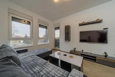 a living room with a couch and a flat screen tv at Hemingway Belgrade Apartment in Zemun