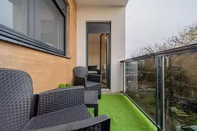 a balcony with chairs and a green lawn at Hemingway Belgrade Apartment in Zemun