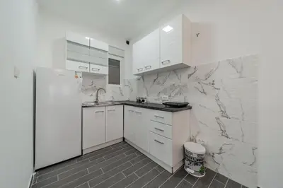 a kitchen with white cabinets and a white refrigerator at Hemingway Belgrade Apartment in Zemun