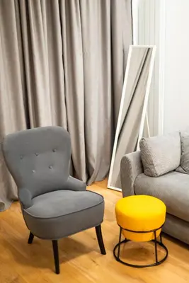 a living room with a chair and a yellow stool at City Center - The Port Apartment with Terrace & Garage in Belgrade