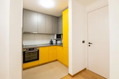 a kitchen with yellow cabinets and a white door at City Center - The Port Apartment with Terrace & Garage in Belgrade