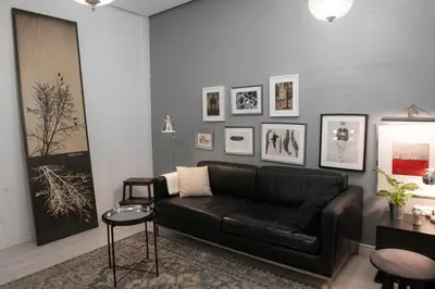 a living room with a black couch and pictures on the wall at Apartment Silicon Valley in Belgrade
