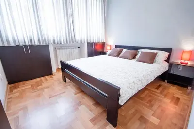 a bedroom with a large bed and a wooden floor at Apartments King Milan, City Center in Belgrade