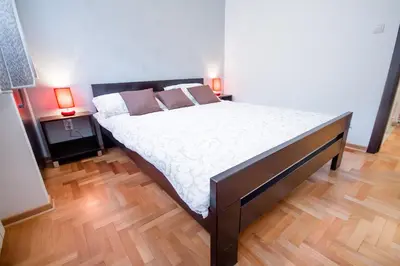 a large bed in a room with two lamps at Apartments King Milan, City Center in Belgrade