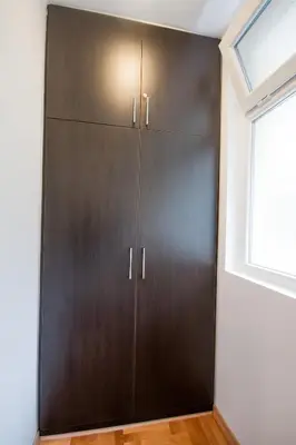 a brown cabinet in a room with a window at Apartments King Milan, City Center in Belgrade
