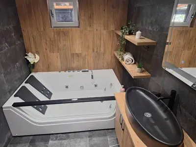 a bathroom with a white tub and a black chair at Apartmani Lux Filipovic in Smederevo