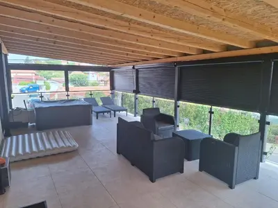 a patio with chairs and tables and blinds at Apartmani Lux Filipovic in Smederevo