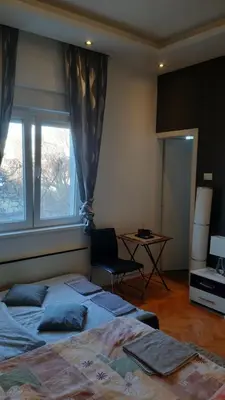 a bedroom with two beds and a table and two windows at Skadarlija Central in Belgrade