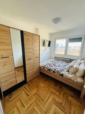 a bedroom with a bed and a large wooden cabinet at Apartment Ninana in Belgrade