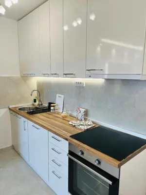 a kitchen with white cabinets and a wooden counter top at Apartment Ninana in Belgrade