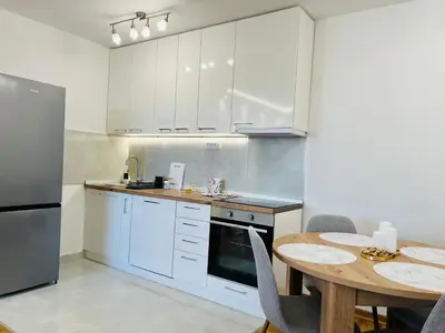 a kitchen with white cabinets and a table with chairs at Apartment Ninana in Belgrade
