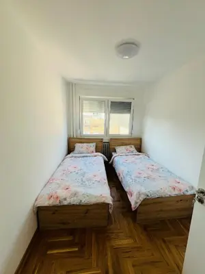 two beds in a room with wooden floors at Apartment Ninana in Belgrade