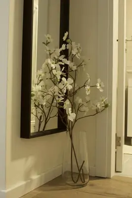 a vase with white flowers in front of a mirror at Aura Apartment - Lovely Apartment with Garage Parking in Belgrade