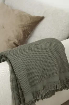 a blanket on top of a couch with a pillow at Aura Apartment - Lovely Apartment with Garage Parking in Belgrade