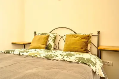 a bed with green and white sheets and yellow pillows at Knez Central Apartment in Belgrade