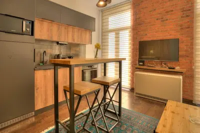 a kitchen with a bar with stools and a television at Knez Central Apartment in Belgrade