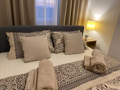 a bed with pillows and towels on top of it at Green Lux Apartment in Inđija