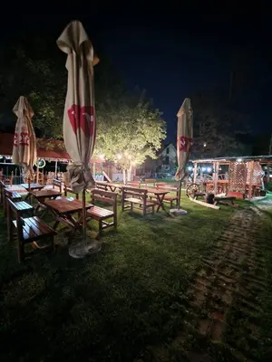 a group of picnic tables with umbrellas in the grass at Etno selo Dukat in Belo Polje