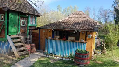 a small house with a blue building with a porch at Etno selo Dukat in Belo Polje