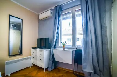a bedroom with a desk and a window with a dresser and a television at Panorama Central-Downtown Studio in Belgrade