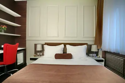 a bedroom with a large bed with a red chair at Belgreat Premium Suites in Belgrade