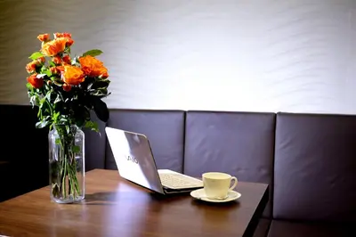 a table with a laptop and a vase with orange flowers at Belgreat Premium Suites in Belgrade