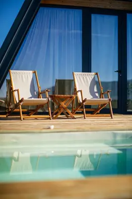 two chairs and a table next to a swimming pool at SunMoon Kosmaj kućice i prostor za događaje in Sopot
