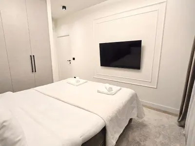 a white room with a bed and a television at Premium Simfonija Apartment in Belgrade