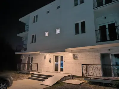 a large white building with stairs leading to a door at Apartman Viktor in Surčin