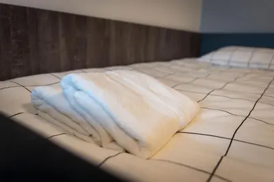 a stack of towels sitting on top of a bed at REAL Suites in Ledine